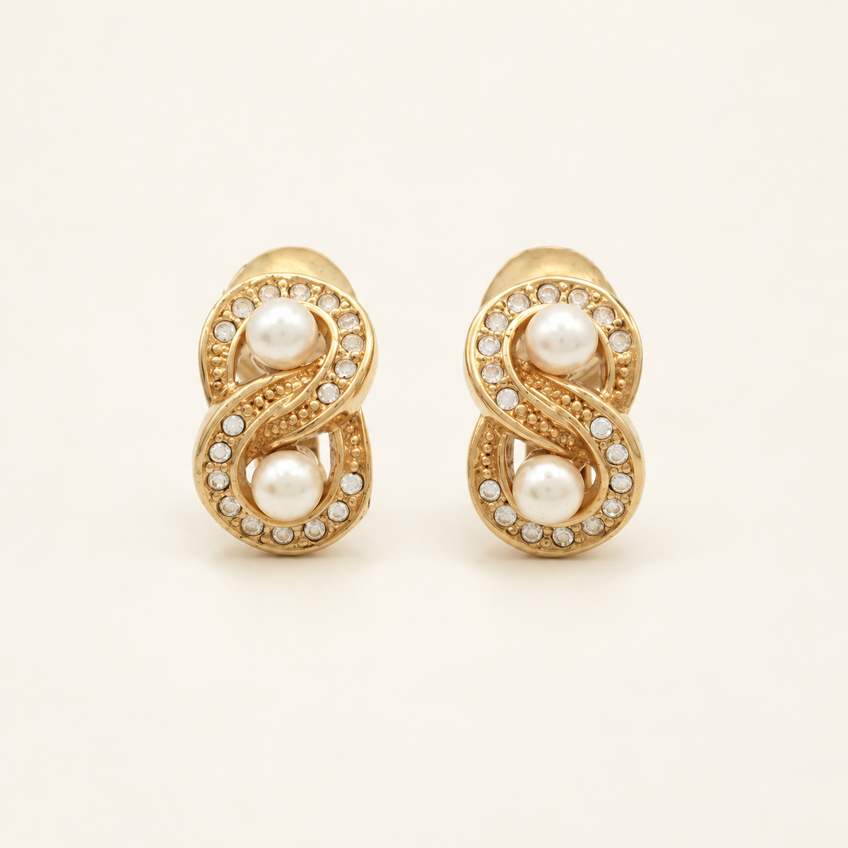 Christian Dior Gold-Tone Faux Pearl Swirl Clip-On Earrings — front view on an ivory background