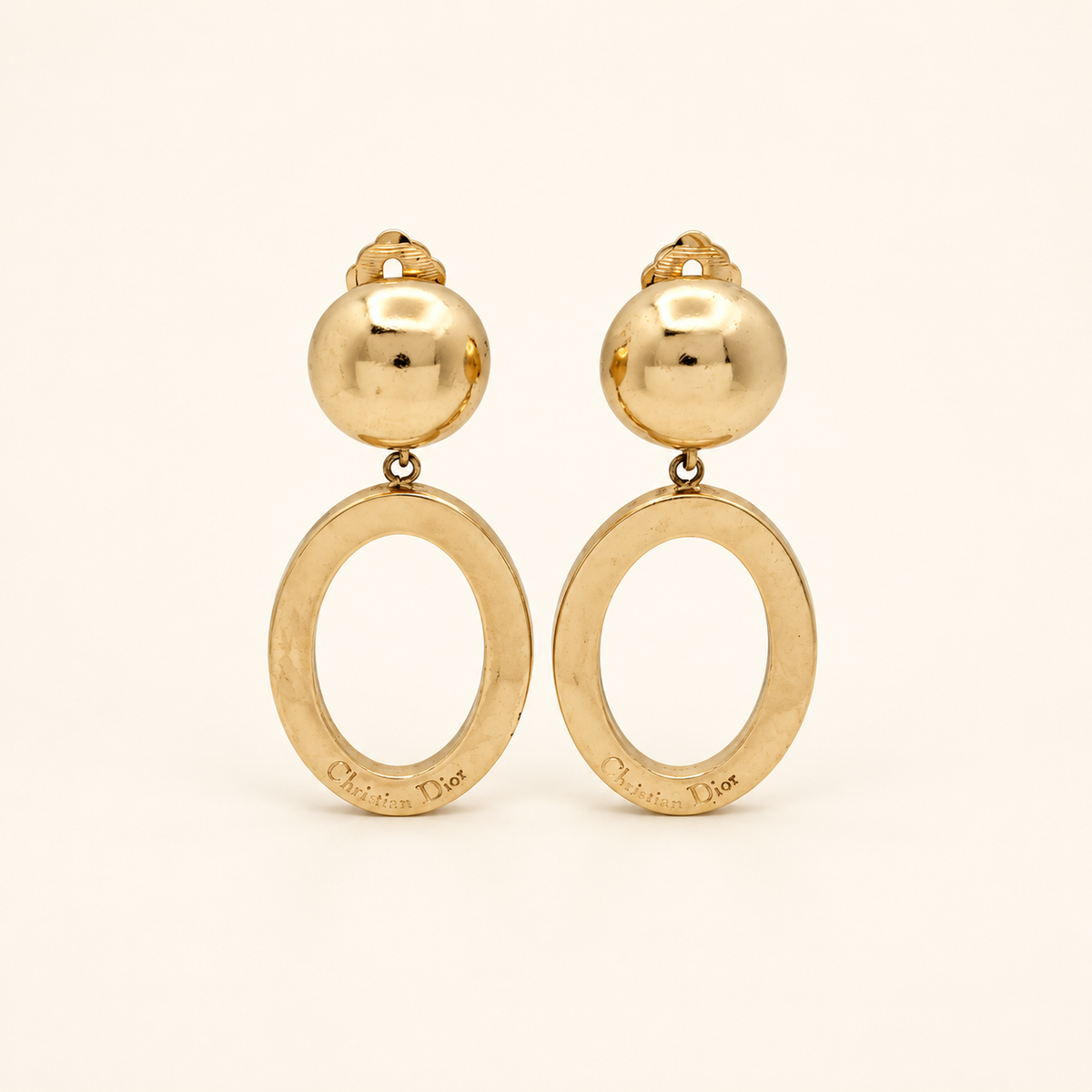 Christian Dior Gold-Tone Oval Drop Clip-On Earrings — front view on an ivory background
