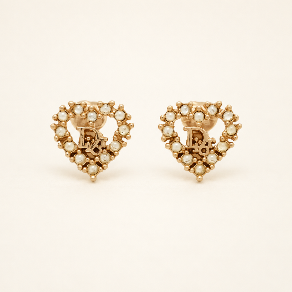 Christian Dior Gold-Tone Heart D Logo Rhinestone Clip-On Earrings — front view on an ivory background