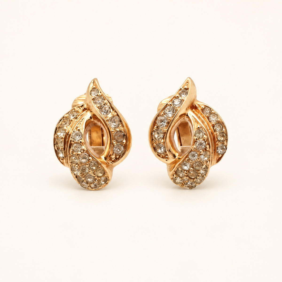 Christian Dior Gold-Tone Teardrop Swirl Rhinestone Clip-On Earrings — front view on an ivory background
