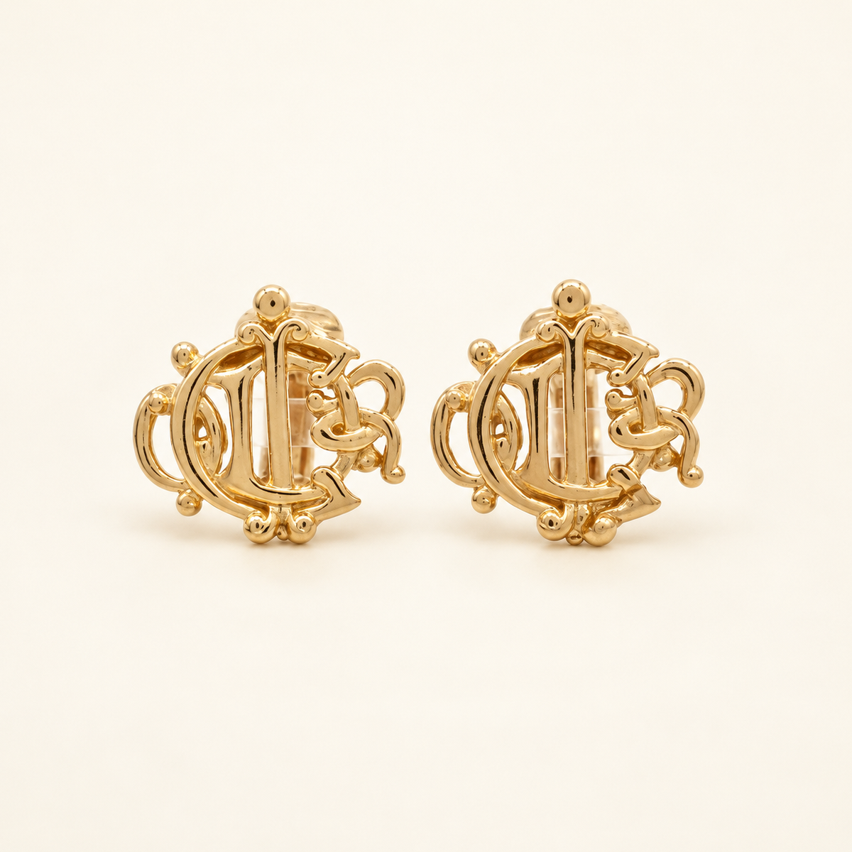 Christian Dior Gold-Tone Crest Logo Clip-On Earrings — front view on an ivory background