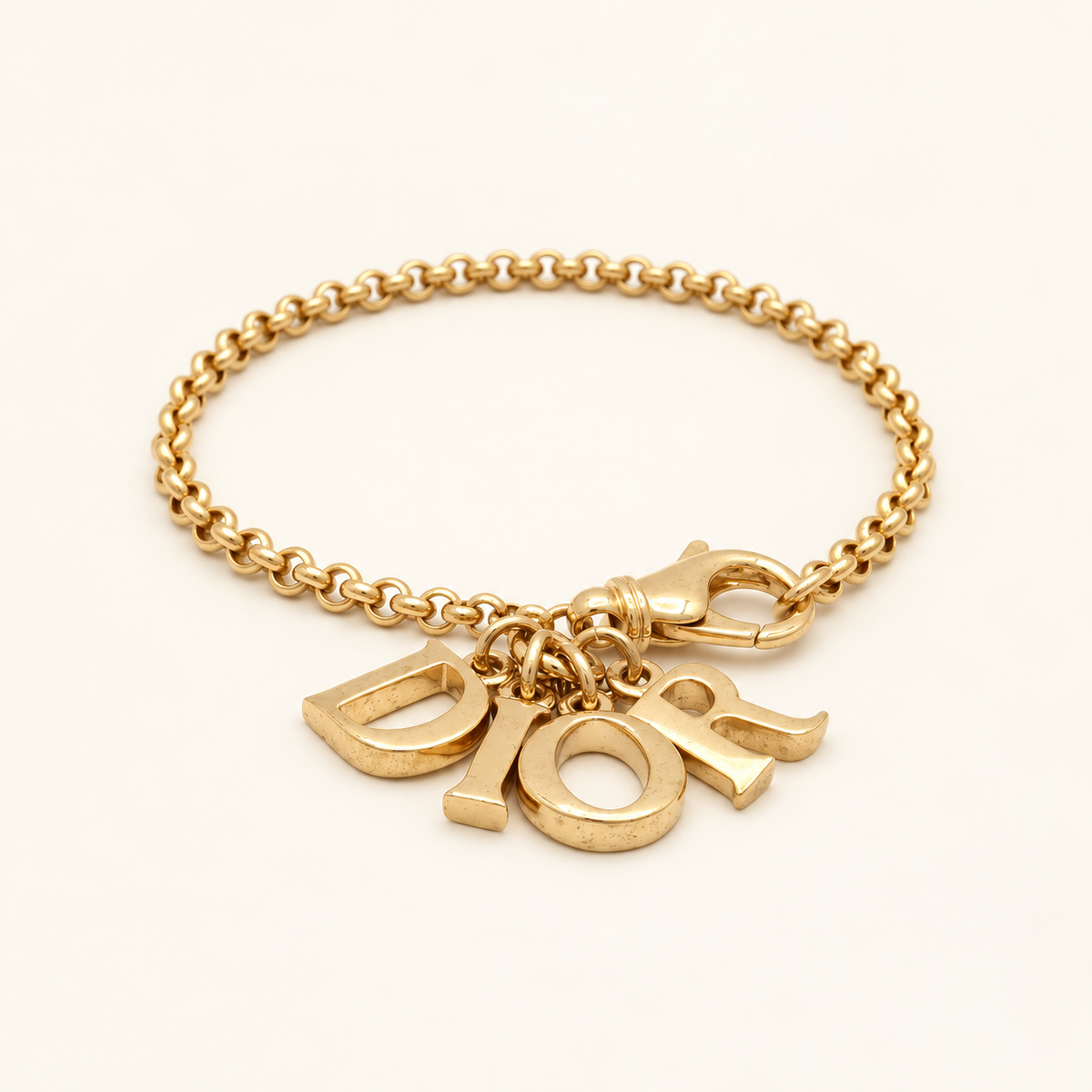 Christian Dior Gold-Tone Dior Letter Charm Bracelet, 18cm — front view on an ivory background