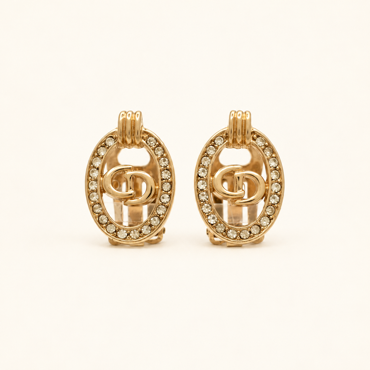 Christian Dior Gold-Tone Oval CD Rhinestone Clip-On Earrings — front view on an ivory background