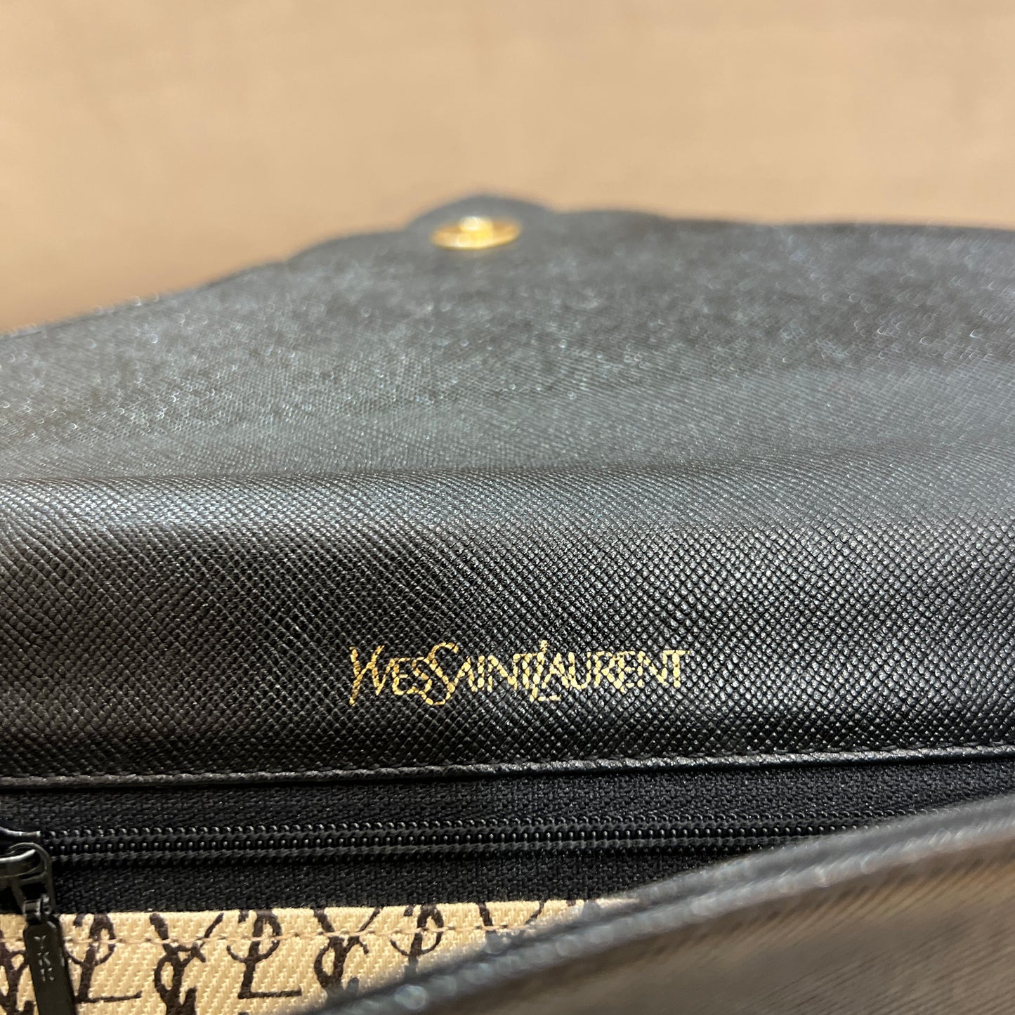 Yves Saint Laurent 復古黑色皮革手拿包，內部飾有經典 Monogram 標誌